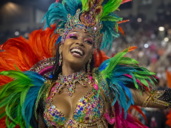 A samba dancer in a feathered costume performing mid-parade